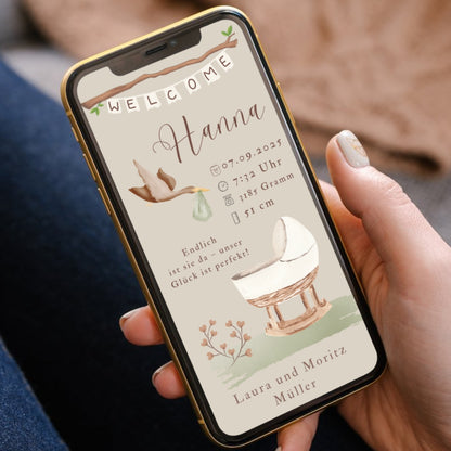 Hand mit Smartphone, auf dem Display eine Geburtsanzeige mit Storch und Wiege